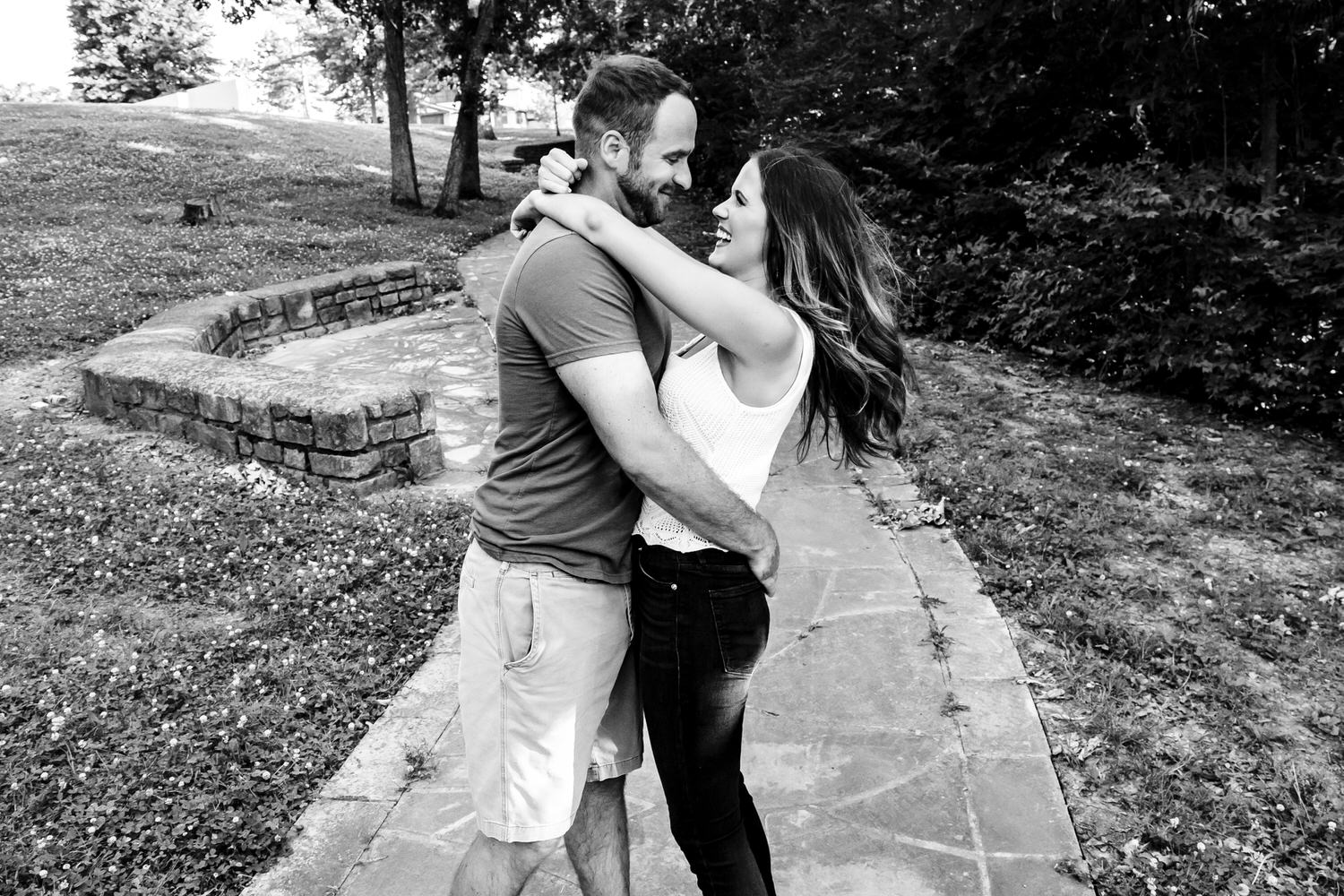 A candid black and white picture of an engaged couple laughing together as they share an embrace during their Kansas City engagement session. 