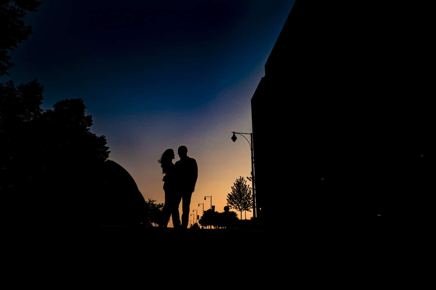 A colorful silhouette of a man and woman dancing outside the Kauffman Center for the Performing Arts during their summer engagement session in Kansas City. 