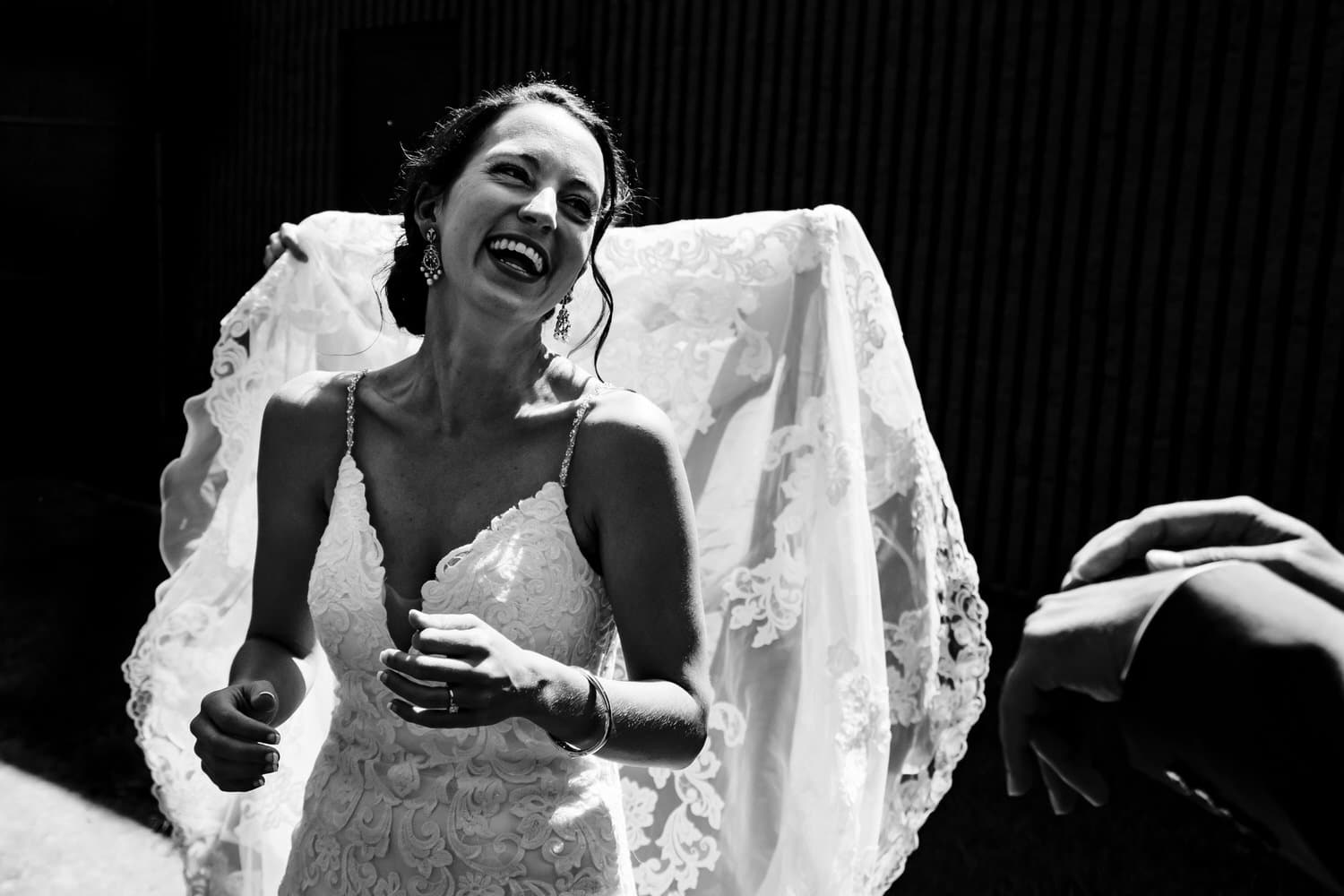 A candid black and white picture of a bride laughing at her groom on the day of their summer wedding ceremony in Kansas City. 