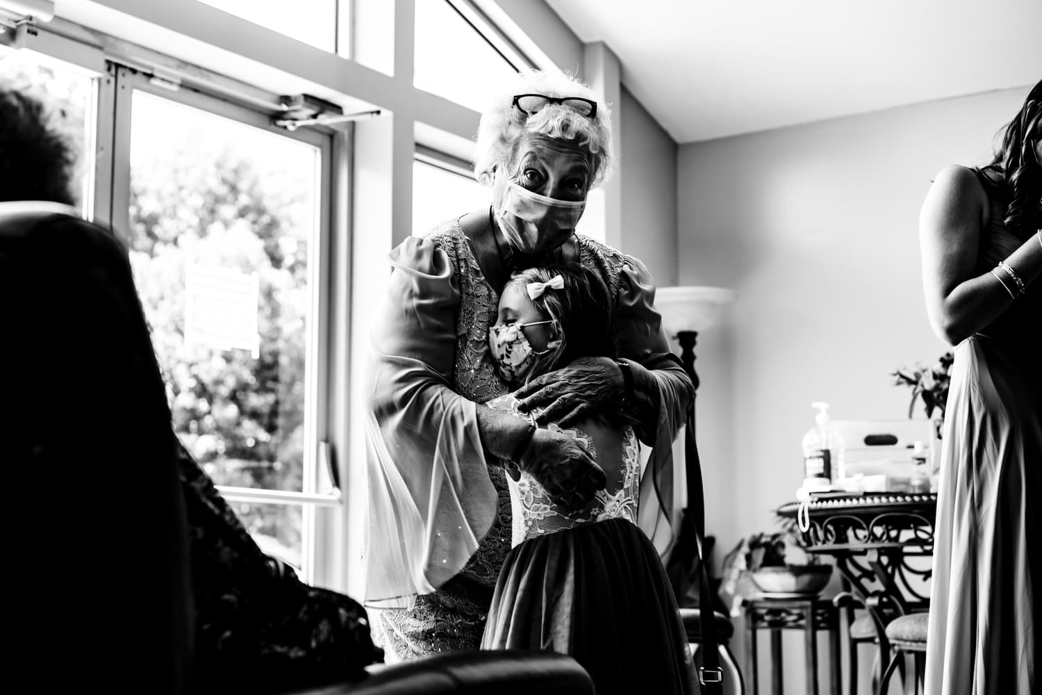 A candid black and white picture of a grandmother hugging her granddaughter close to her chest minutes before a wedding ceremony. 