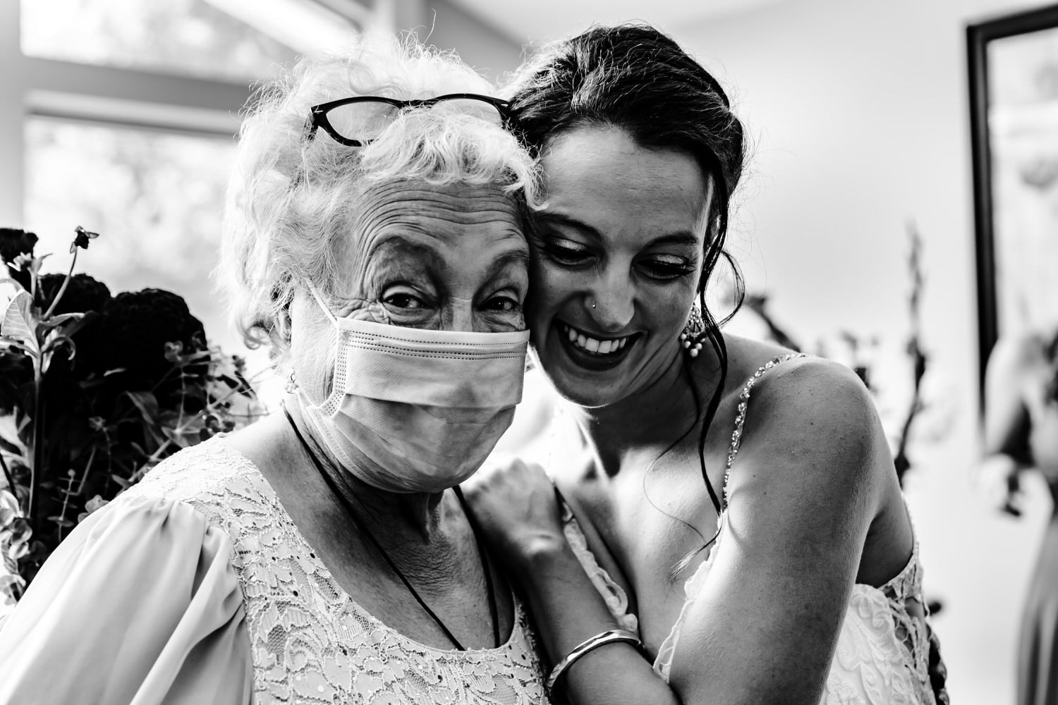 A candid black and white picture of a grandmother hugging her granddaughter close to her chest minutes before a wedding ceremony. 