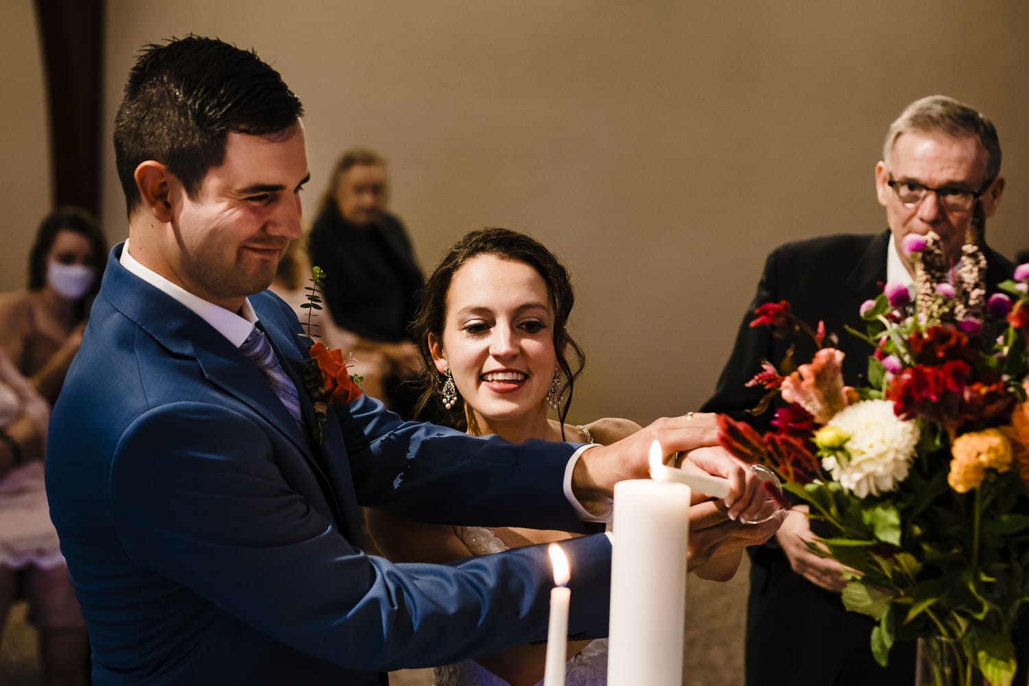A colorful, candid picture of a bride and groom lighting a unity candle during their intimate wedding ceremony. 