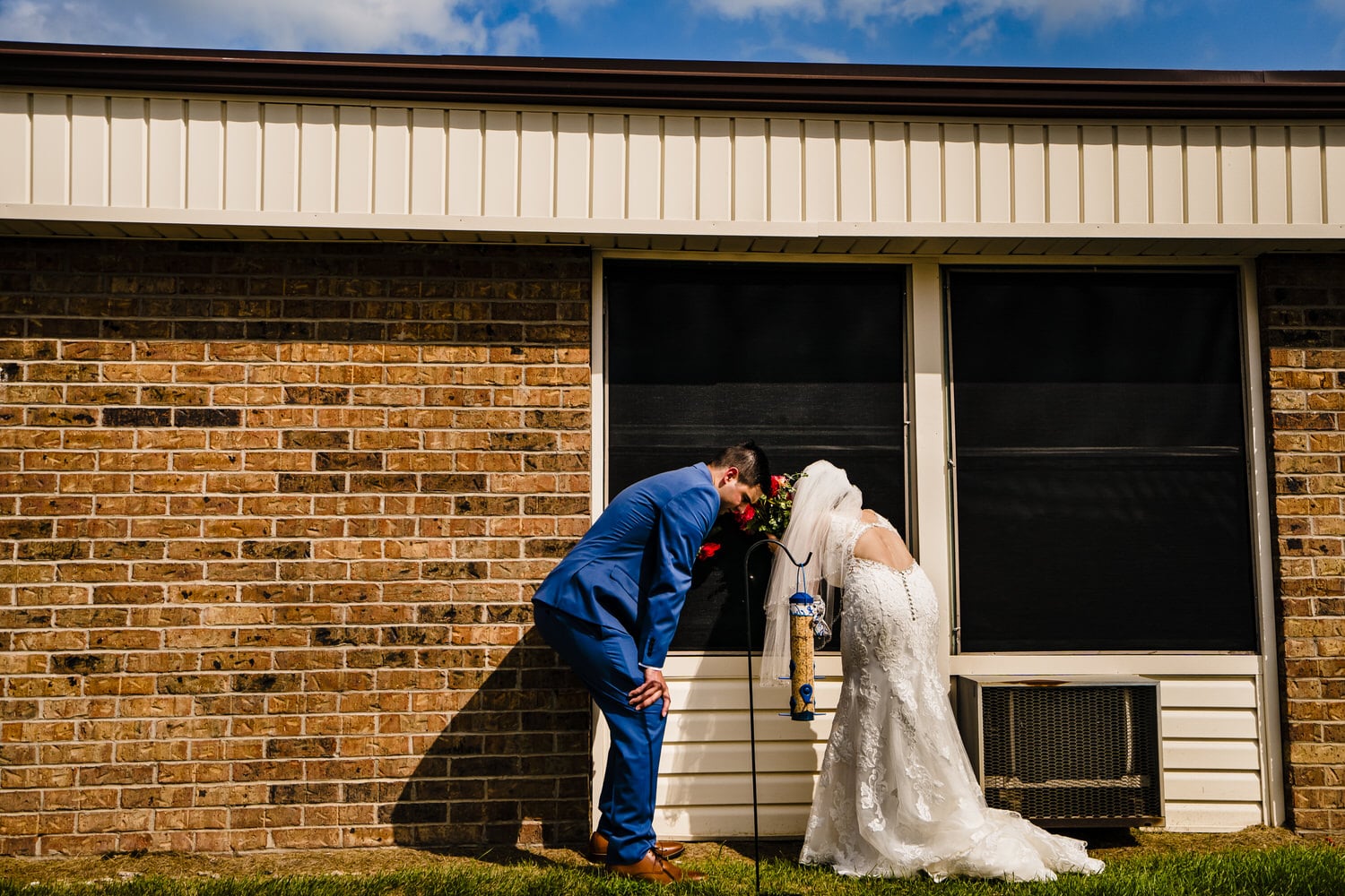 A wide picture of a bride and groom looking into the window of a building. 