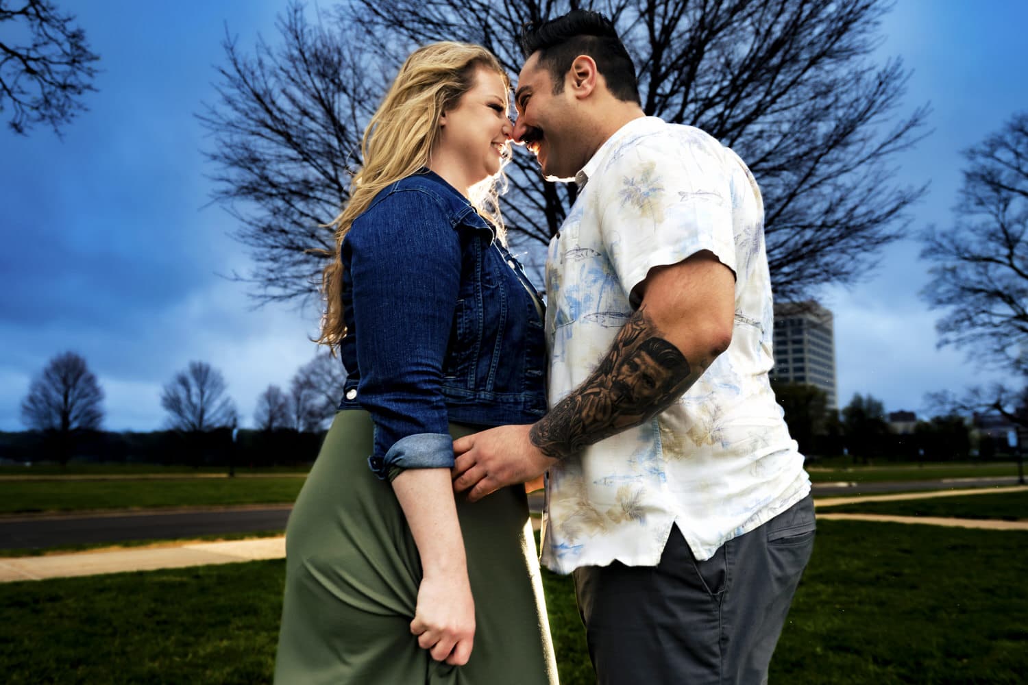 A candid, colorful picture of an engaged couple leaning in, nose to nose, with big smiles on their faces during their moody engagement session at Liberty Memorial in Kansas City. 