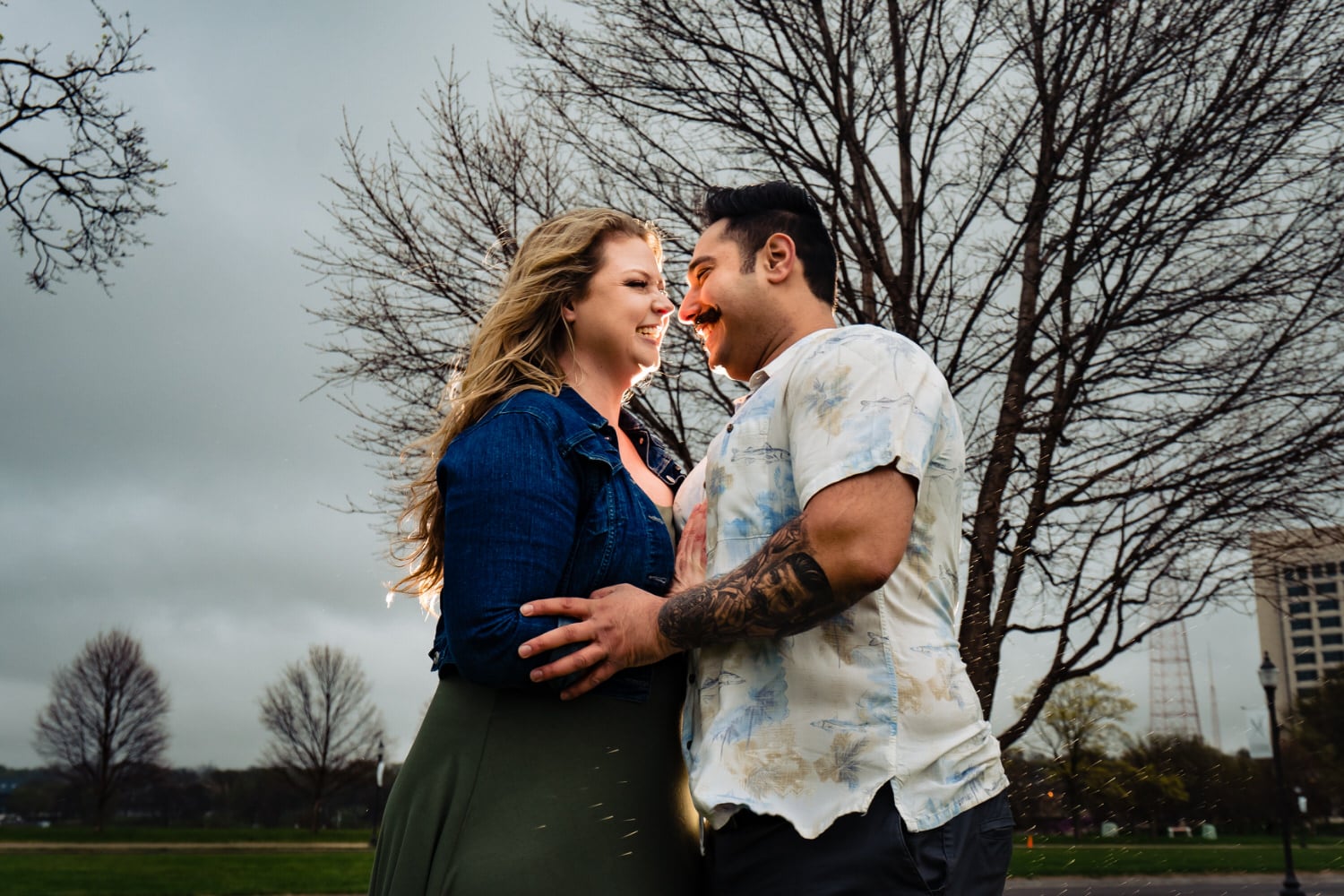 A candid picture of an engaged couple learning in to share a kiss and hug during their moody engagement session at Liberty Memorial in Kansas city. 
