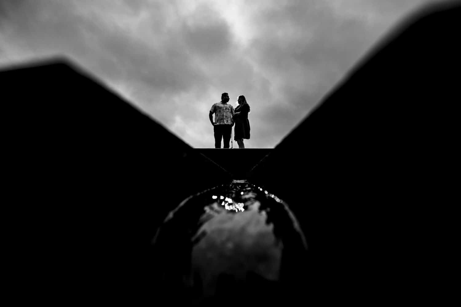 A formal black and white portrait of an engaged couple standing against a stormy sky during their Liberty Memorial engagement session. 