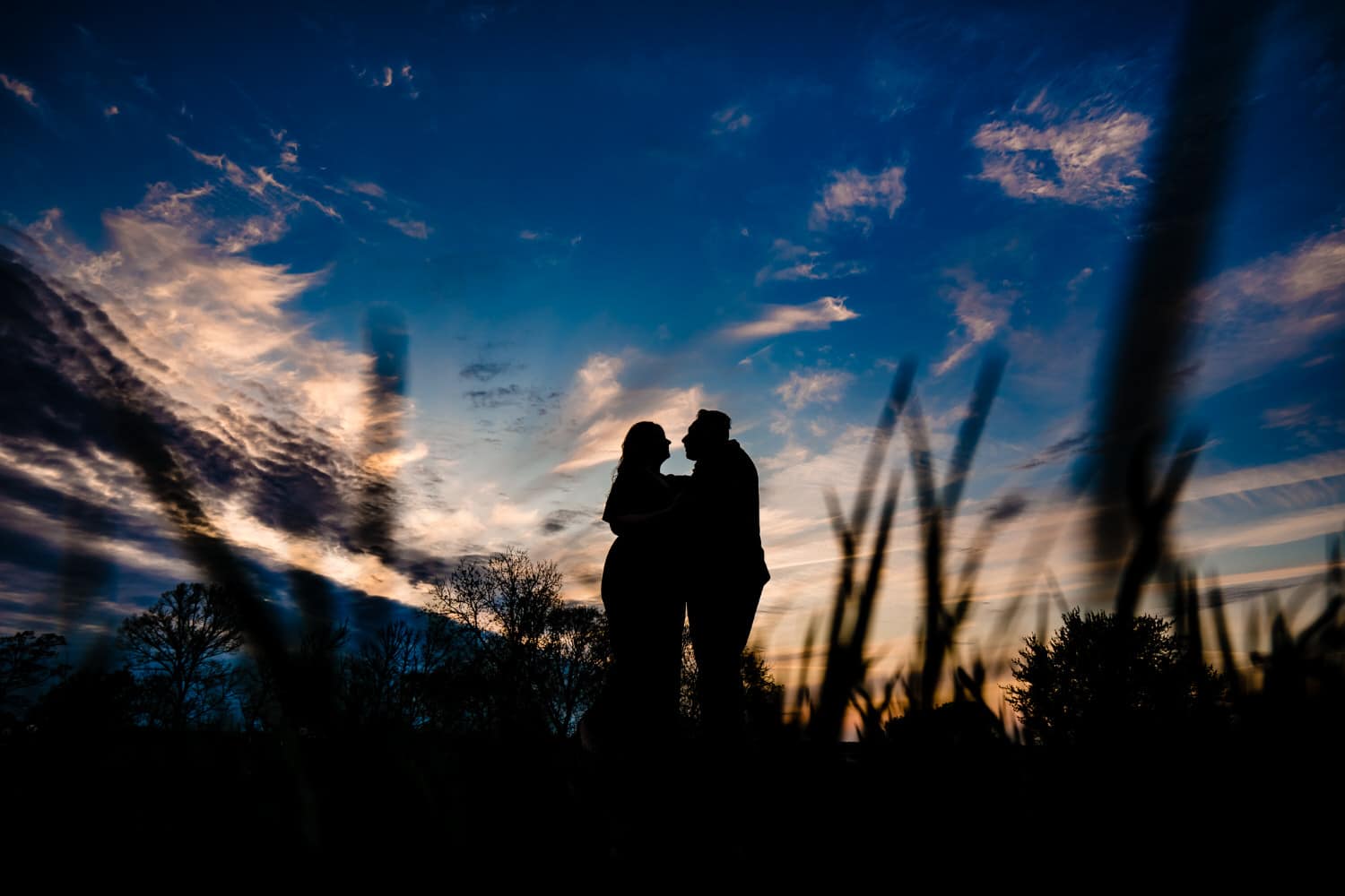 A dramatic silhouette of an engaged couple sharing an embrace during their engagement session. 