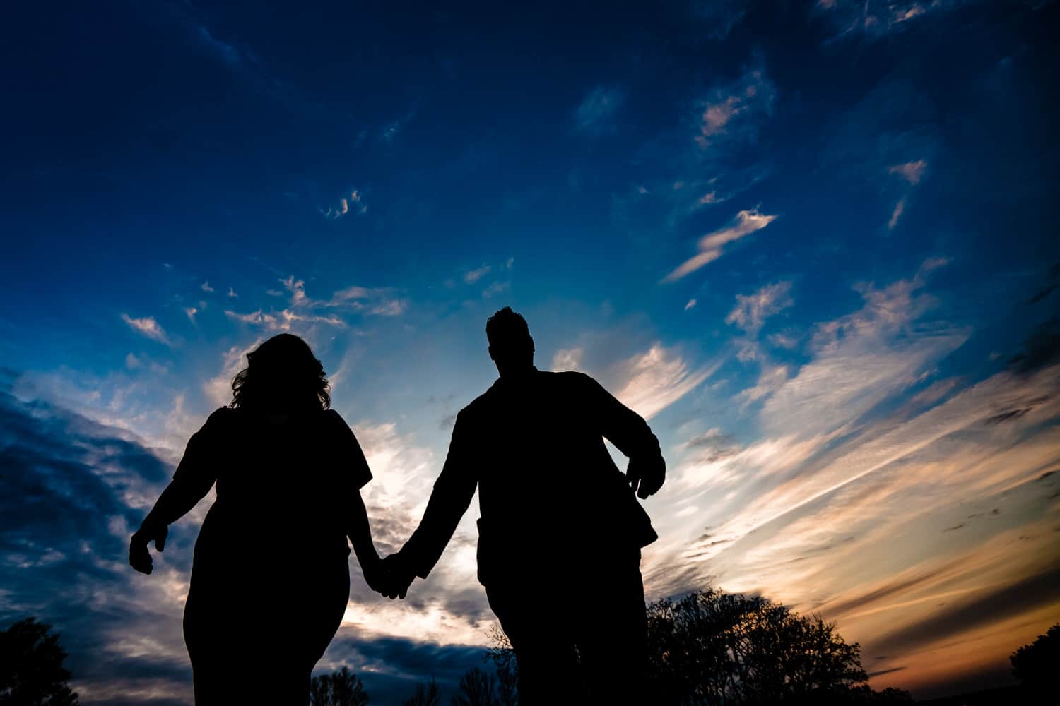 A dramatic silhouette of an engaged couple sharing an embrace during their engagement session. 