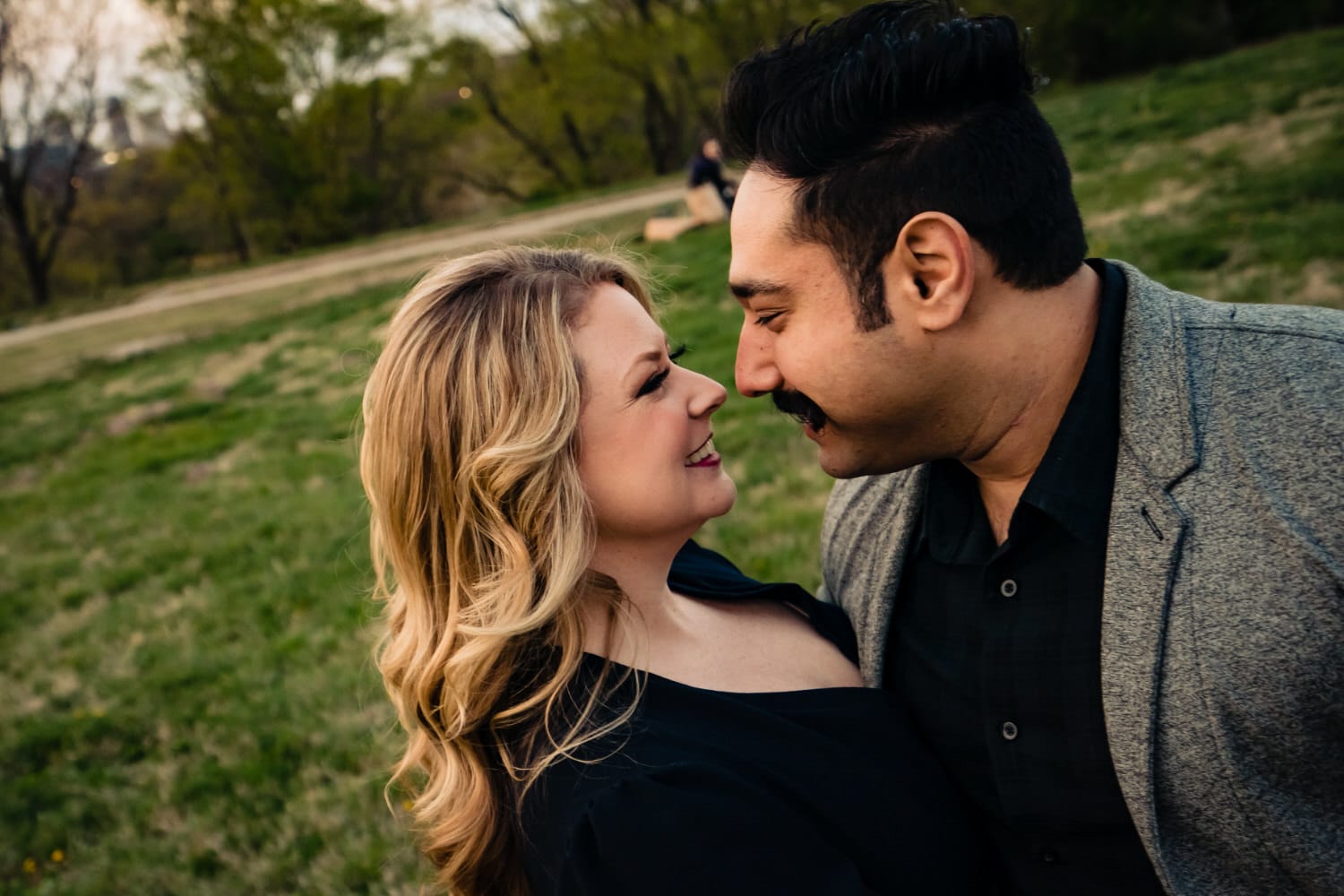 A candid, close-up picture of an engaged couple sharing an embrace and smiling at each other during their downtown Kansas City engagement session. 