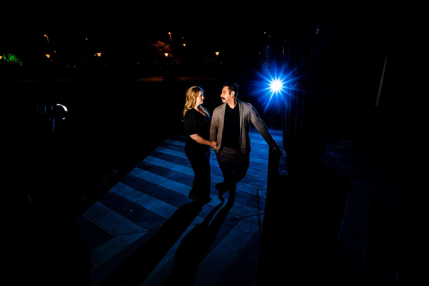 A posed portrait of an engaged couple on the terrace of the downtown Kansas City Convention Center during their nighttime engagement session. 