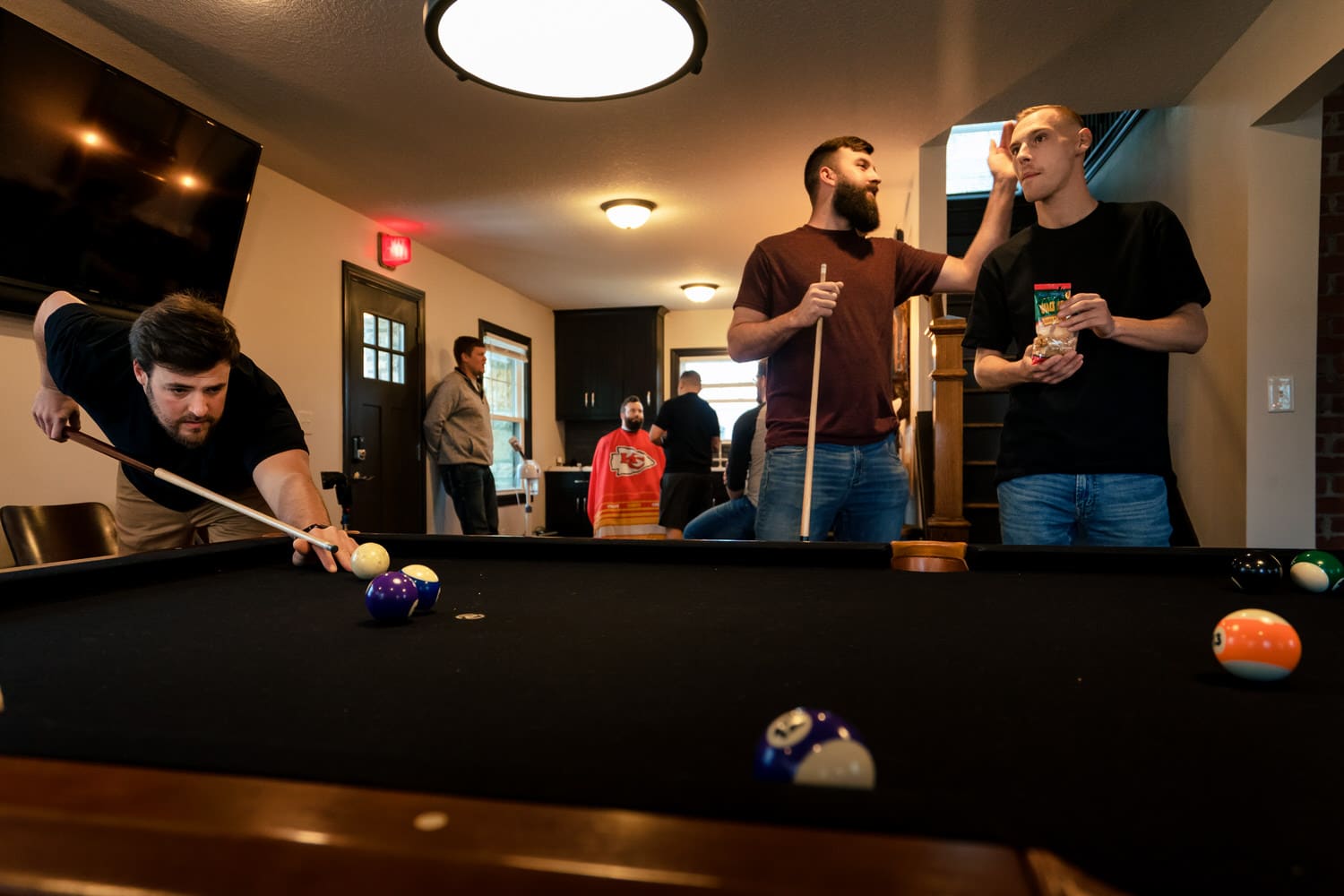 A candid picture of a group of men playing pool in The Cottage at The Farmhouse KC Event Venue. 
