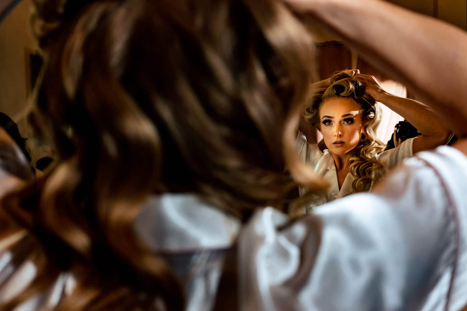 A candid picture taken over the shoulder of a bride as she takes her hair out of curlers on the morning of her spring wedding in Kansas City. 