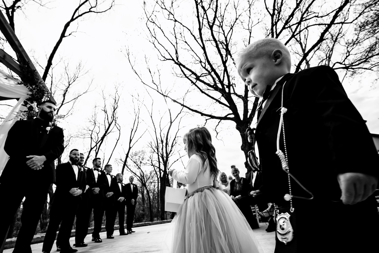 A candid black and white picture of a flower girl and ring bearer walking down the aisle during a spring wedding in Kansas City. 