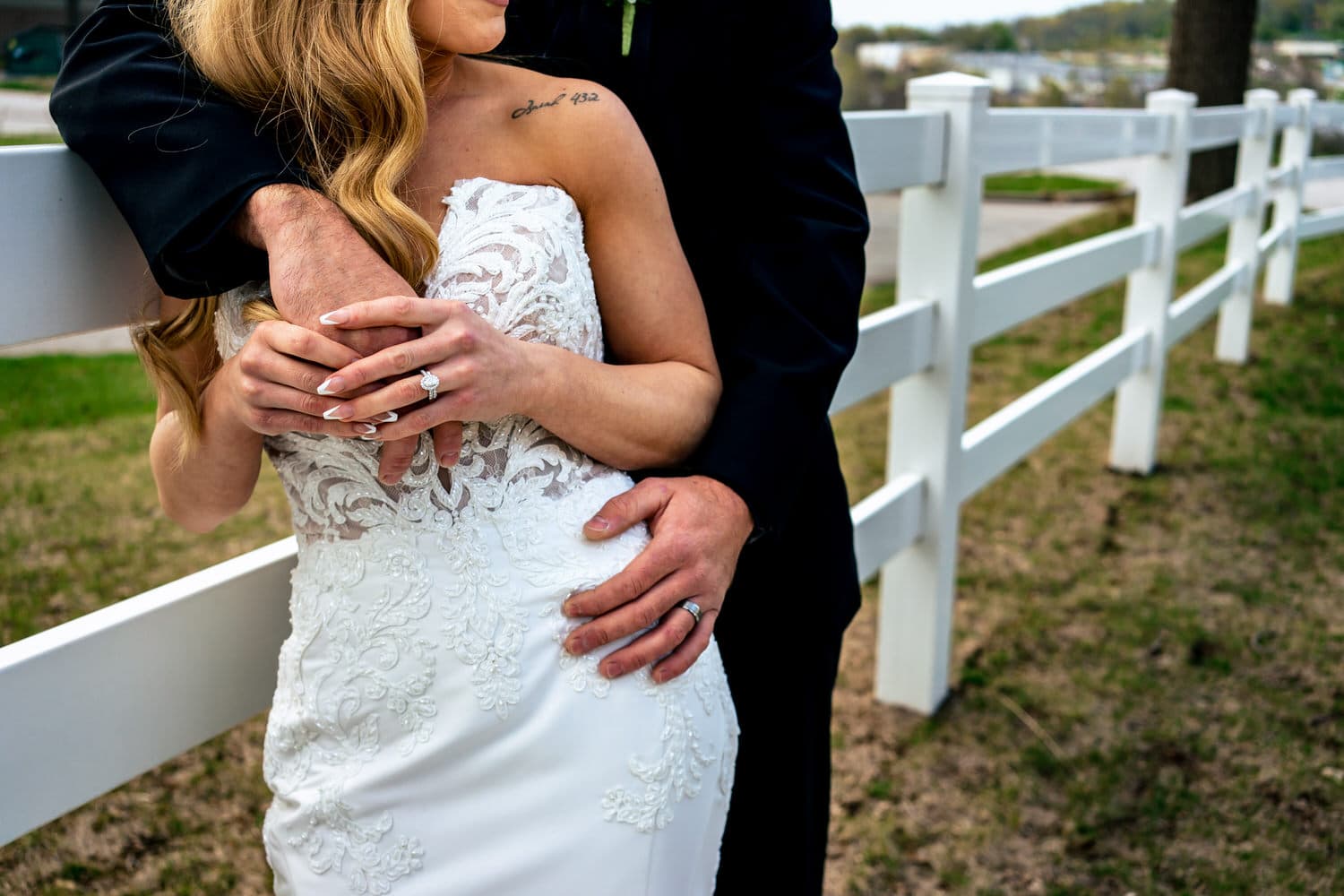 A close-up picture of a bride holding her groom's hand, his other hand visible on her waist. 