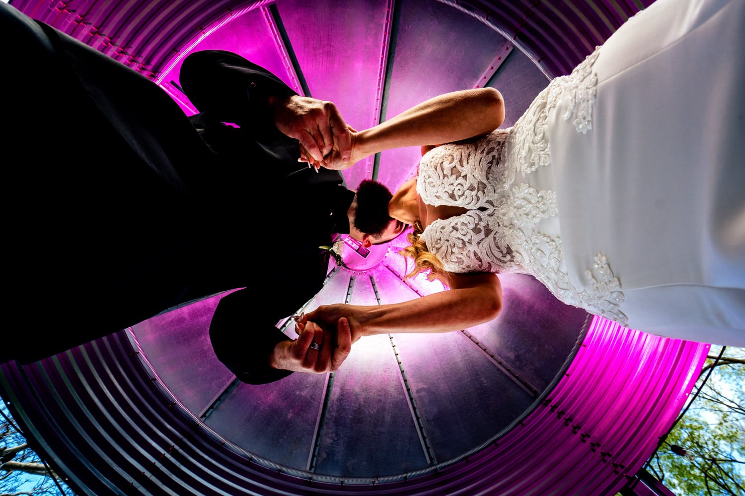 A colorful portrait taken from below, looking up of a bride and groom leaning in to share a kiss on their spring wedding day. 