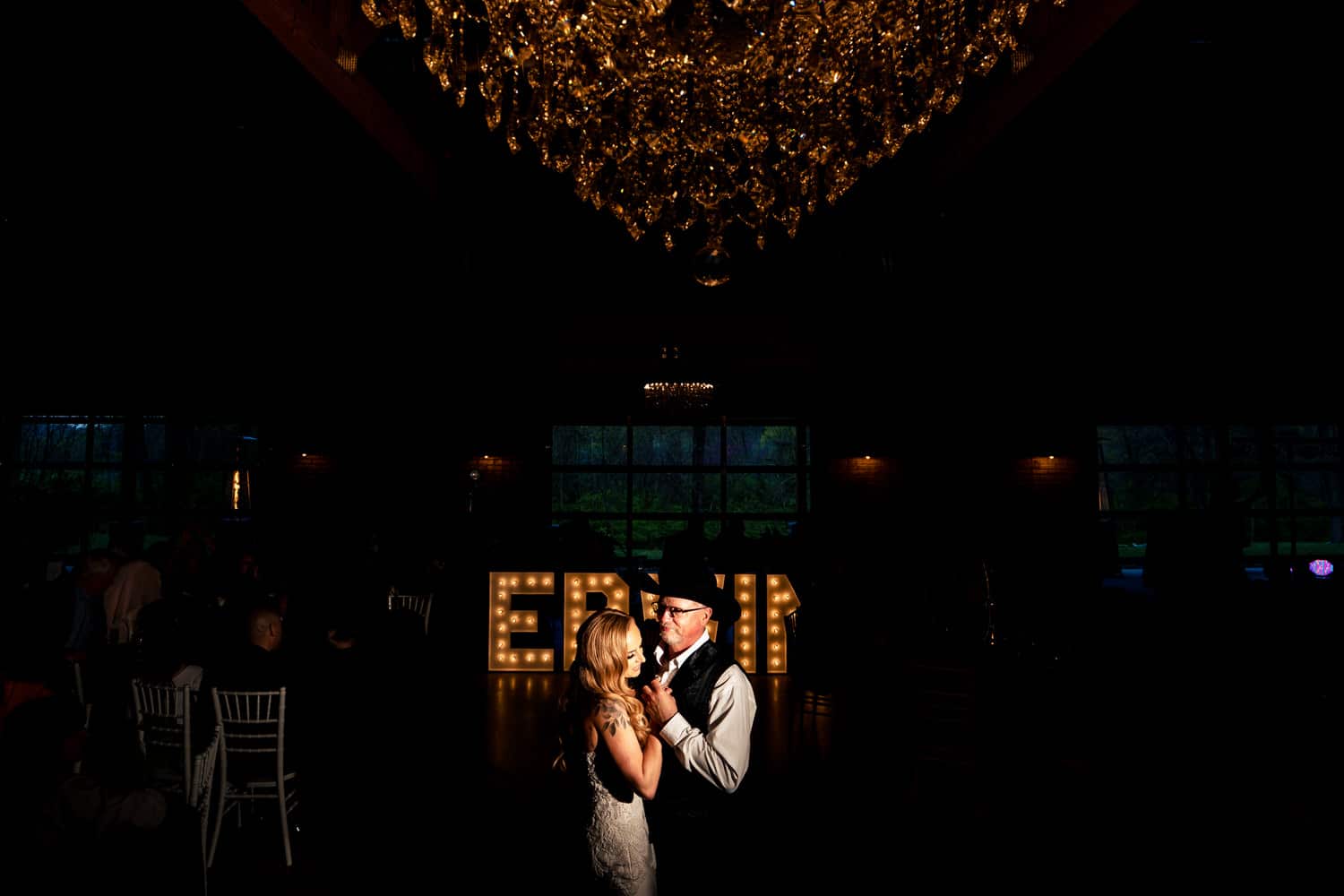 A candid, wide picture of a bride dancing with her father during her wedding reception at The Farmhouse KC Event Venue. 