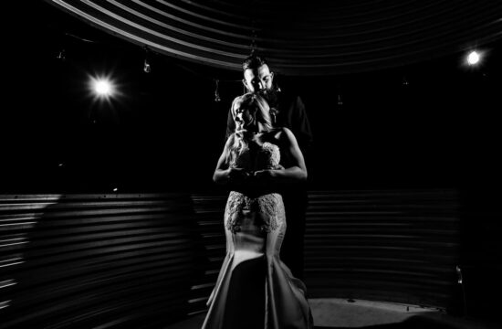A dramatic black and white picture of a bride and groom sharing an embrace on their wedding night.