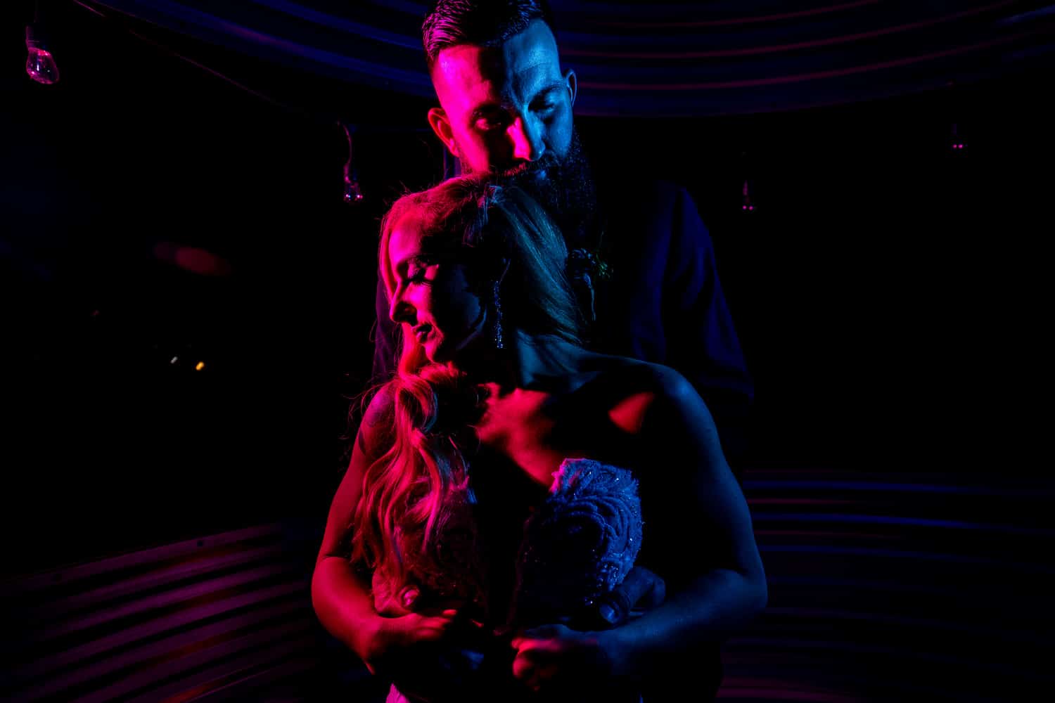 A dramatic, colorful picture of a bride and groom sharing an embrace on their wedding night. 