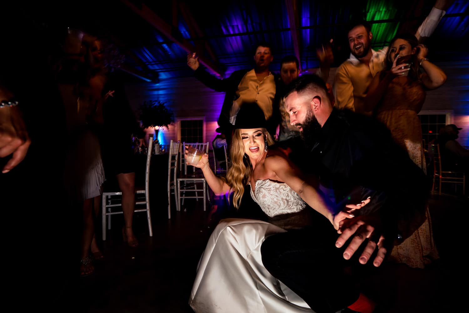 A colorful, candid picture of a group of wedding guests crazily dancing during a spring wedding reception at The Farmhouse KC Event Venue. 