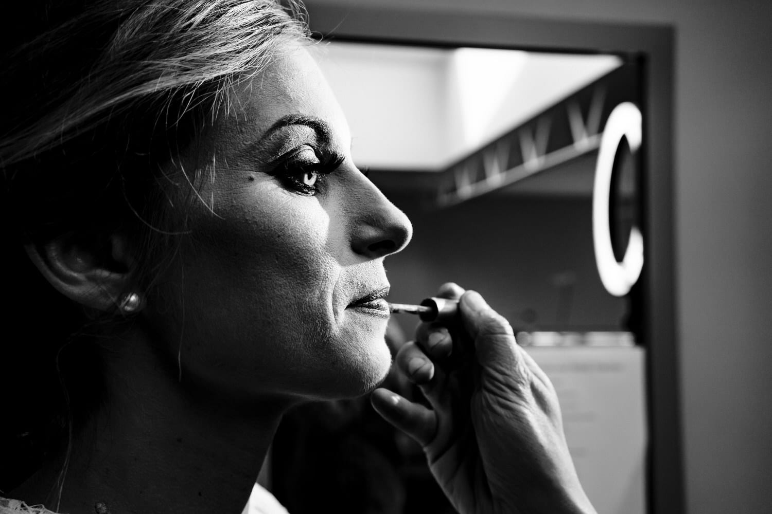 A bold, black and white picture of a woman putting lip gloss onto another woman. 