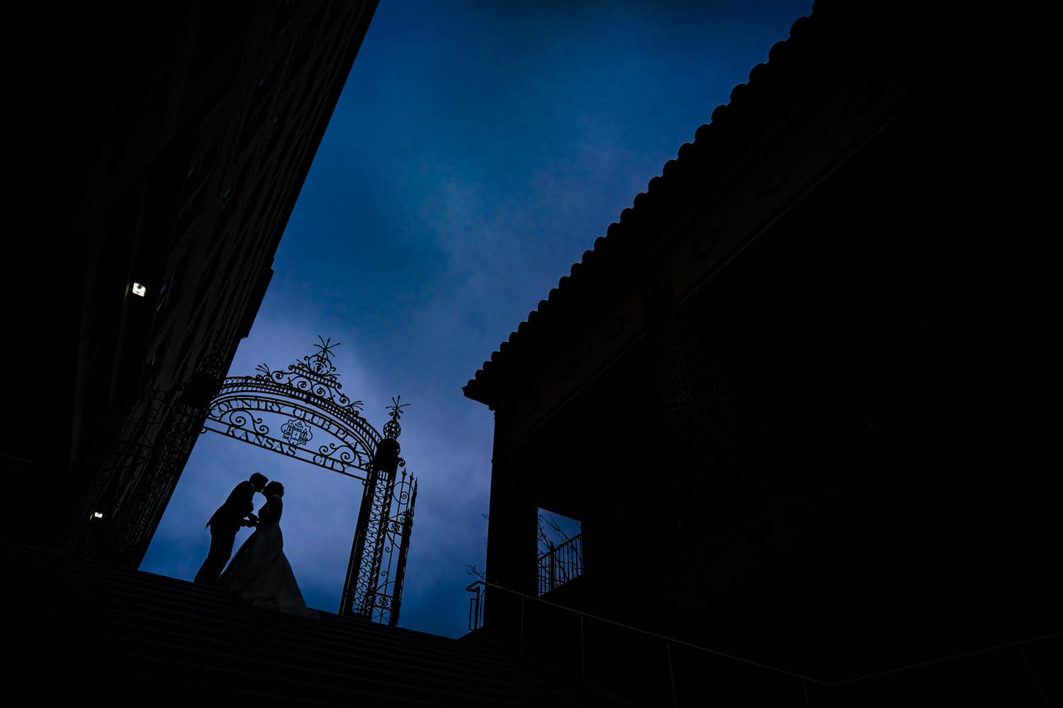 A dramatic, bold silhouetted portrait of a bride and groom sharing a kiss just after sunset on their Kansas City wedding day. 