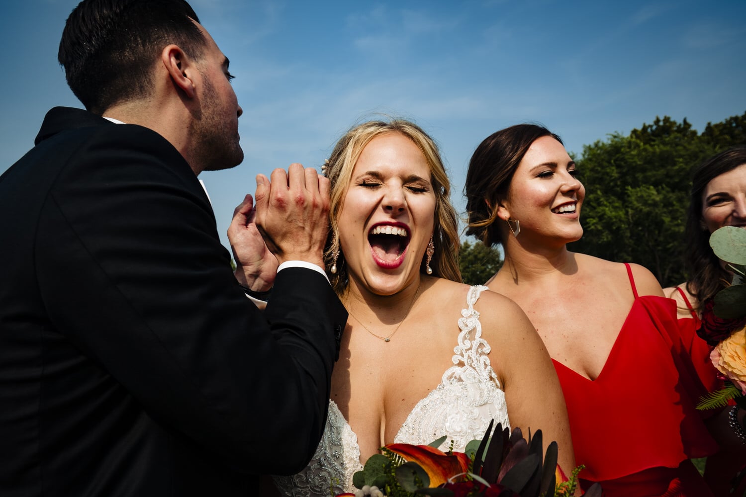 A candid, close-up picture of a bride laughing with her mouth wide open. 
