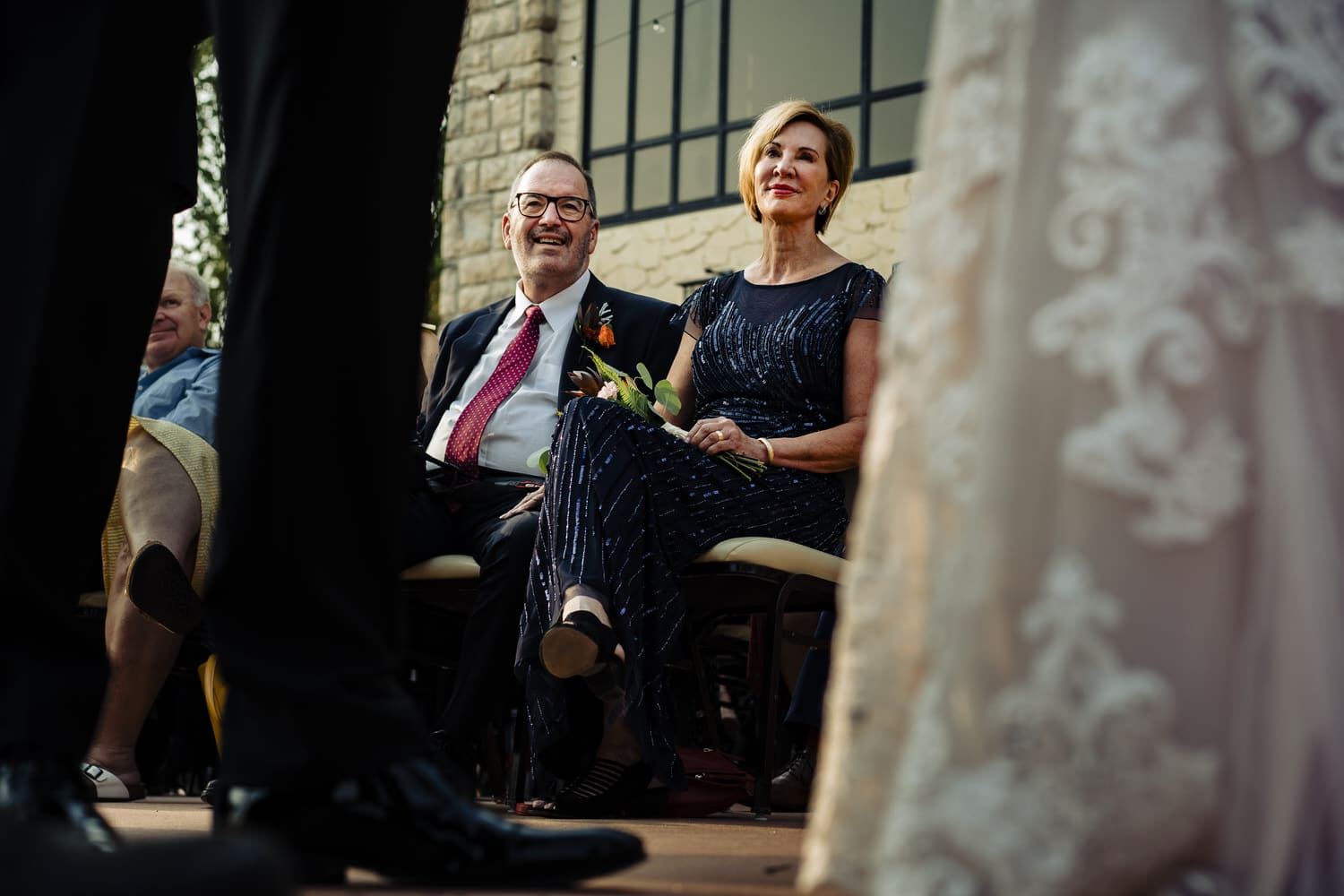 A candid picture of a groom's parents watching a wedding ceremony at Lake Quivira Country Club. 