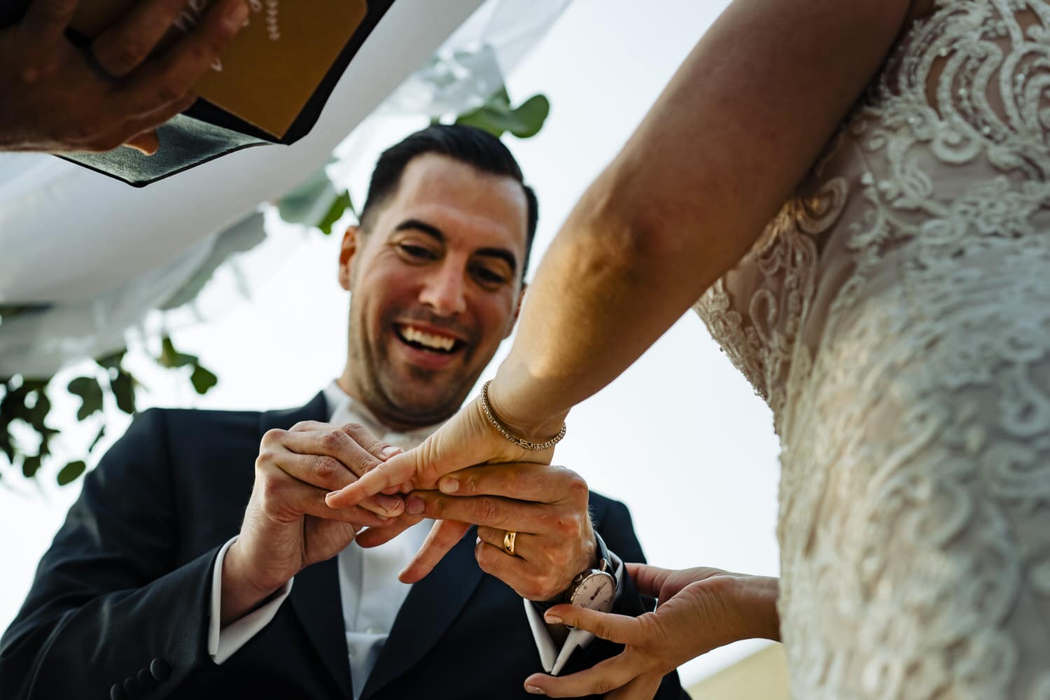 A colorful, candid picture of a groom putting a wedding band on his bride's finger during their fall wedding ceremony at Lake Quivira Country Club in Kansas City. 