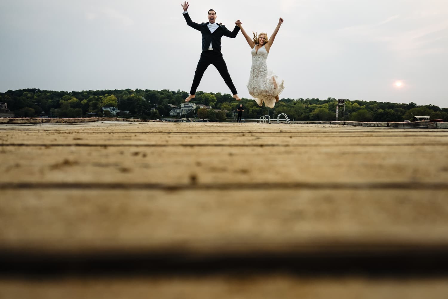 A candid, colorful picture of a bride and groom jumping up in celebration on their wedding day in Kansas City. 