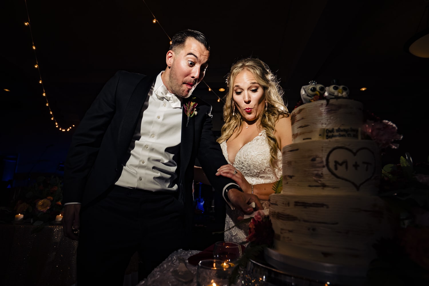 A colorful, candid picture of a bride and groom laughing together as they cut a wedding cake. 