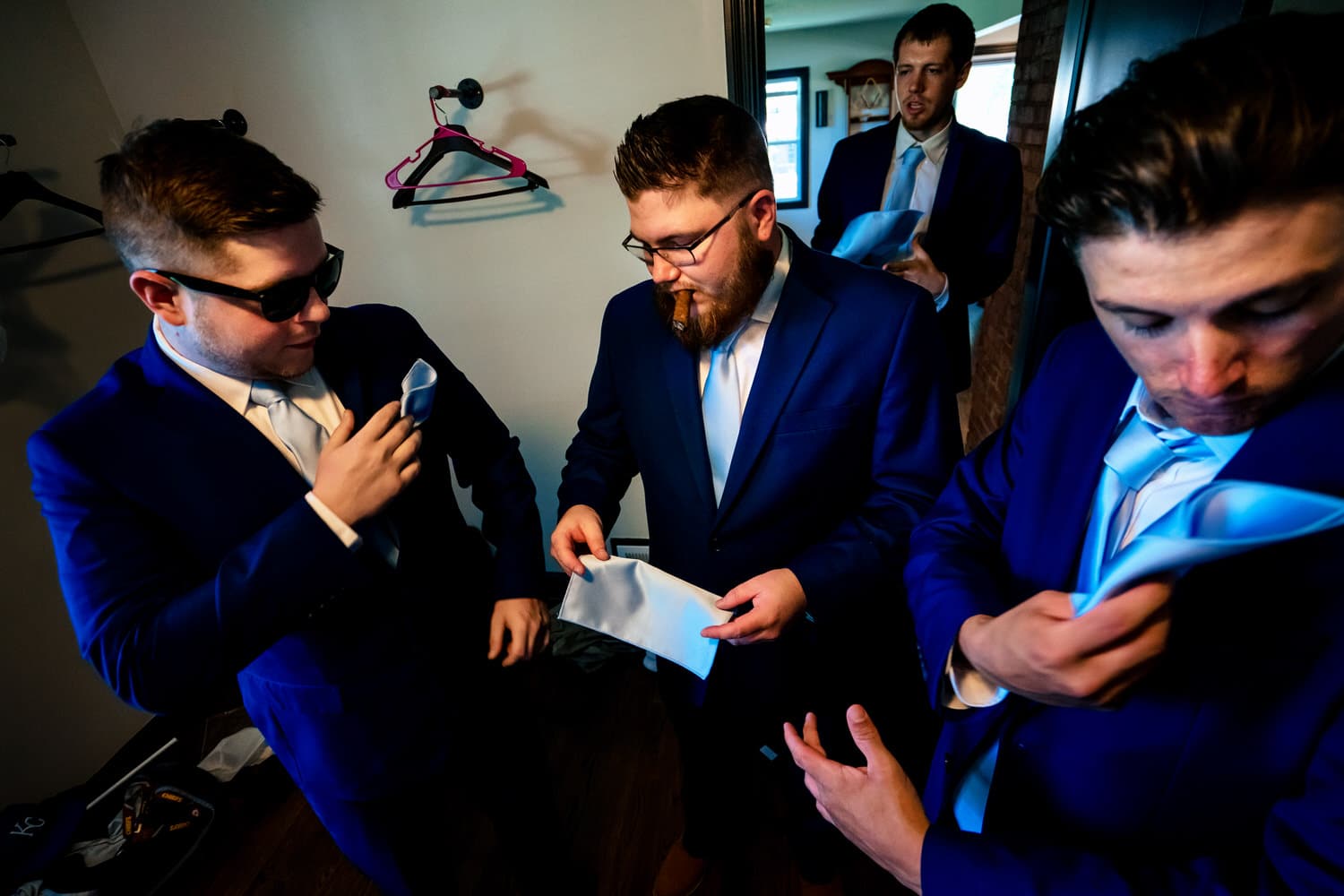 A colorful, candid picture of a group of groomsmen folding their pocket squares. 