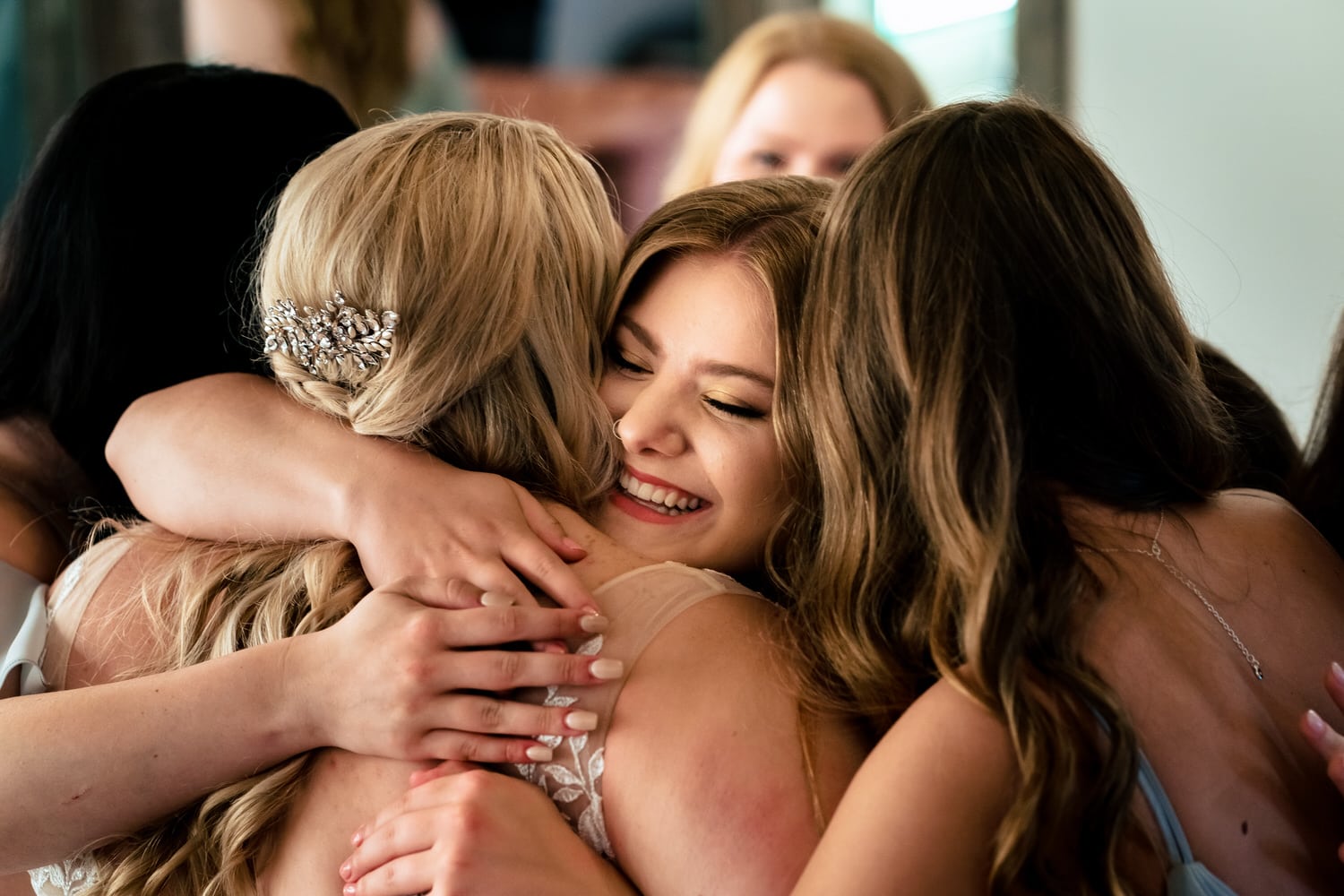 A colorful, candid picture of a bride hugging a group of bridesmaids moments after she put on her wedding gown. 