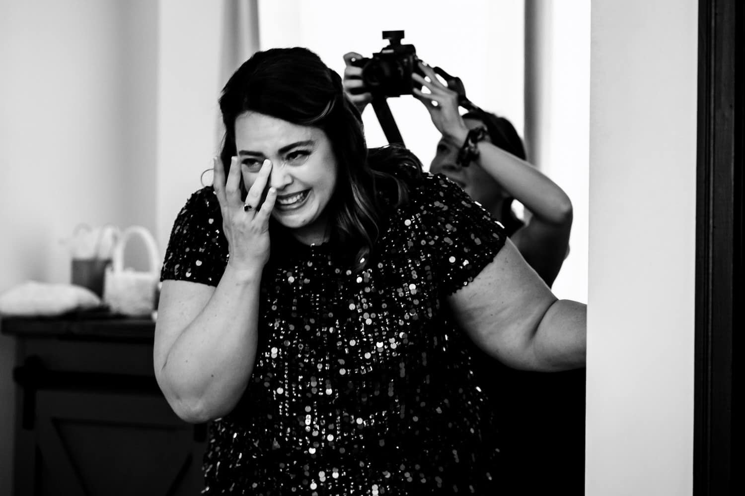 A candid black and white picture of a bride's mom breaking down in tears as she watches her daughter. 
