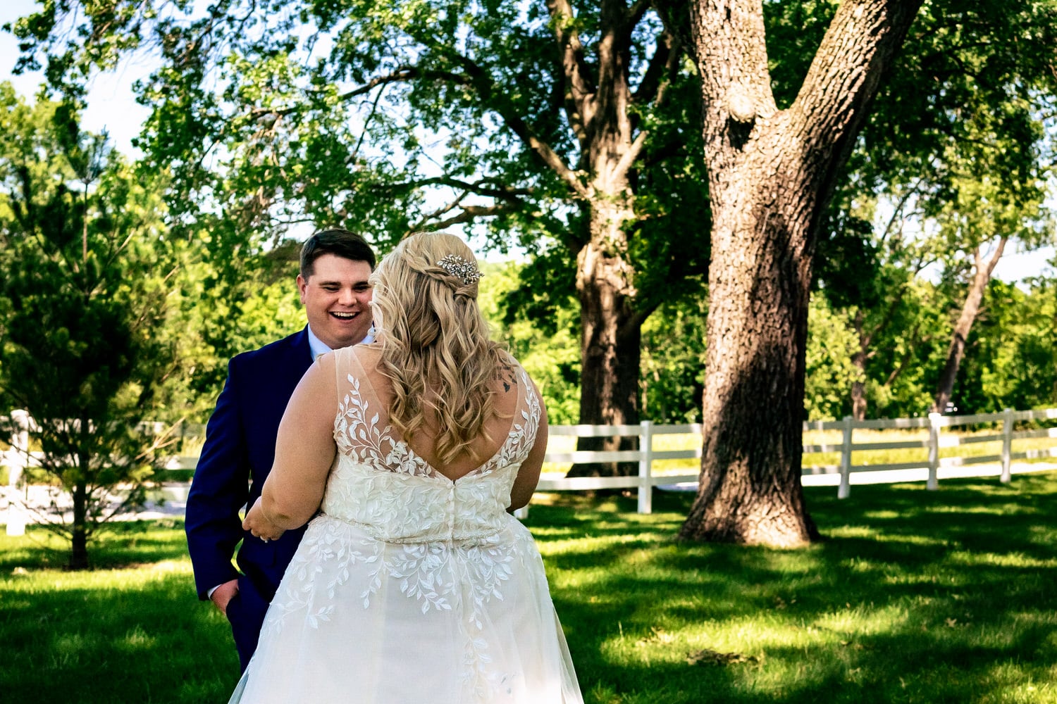 A colorful picture of a groom seeing his bride for the first time on their summer wedding day at The Farmhouse KC Event Venue. 
