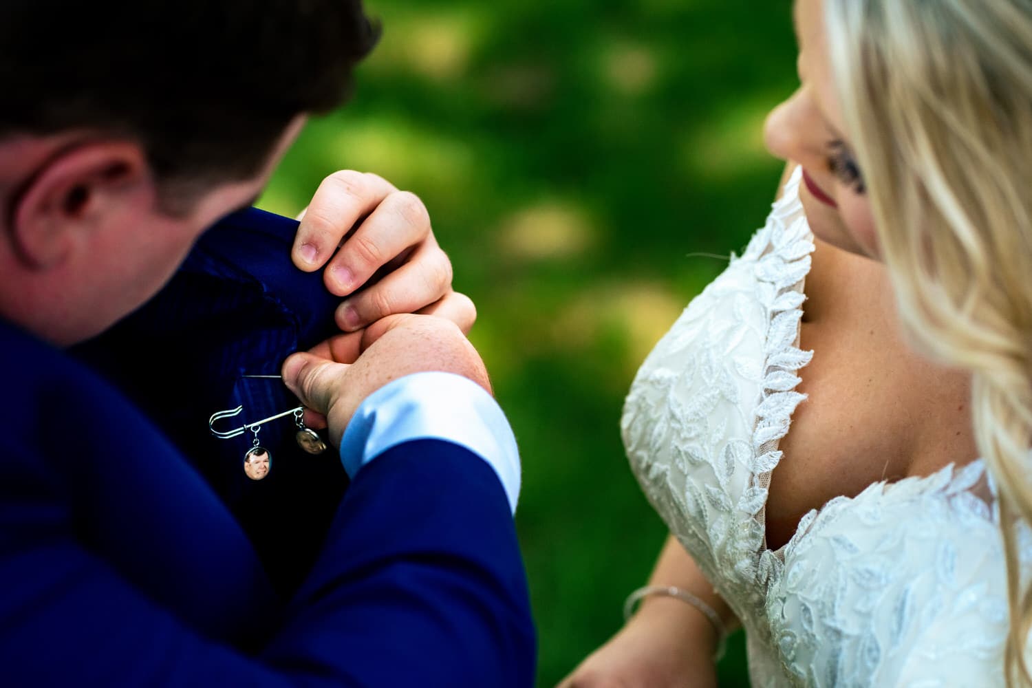 A colorful, candid picture of a groom pinning a gift from his bride into the pocket of his tuxedo. 