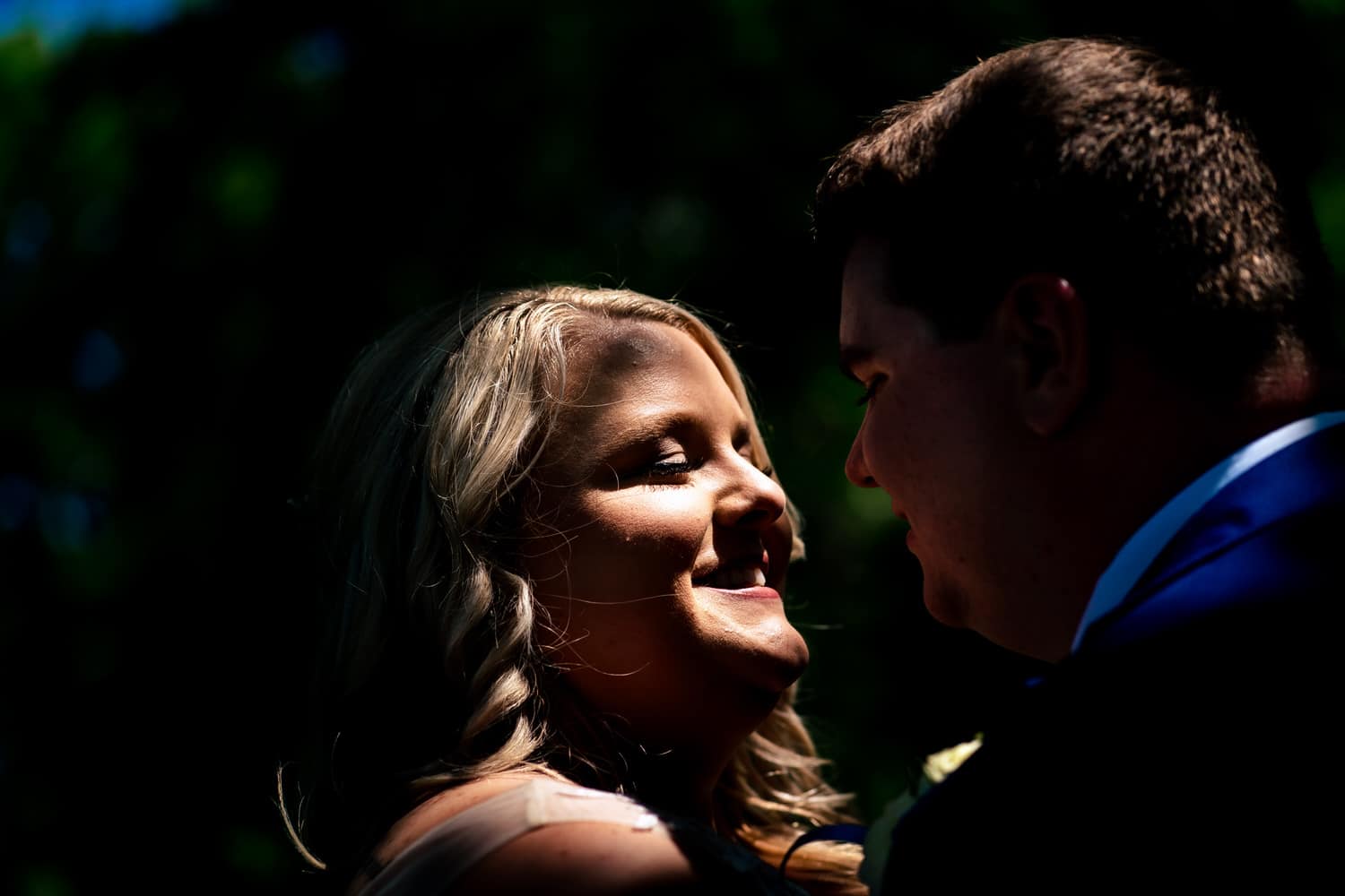An up-close picture of a bride smiling up at her groom on their summer wedding day. 