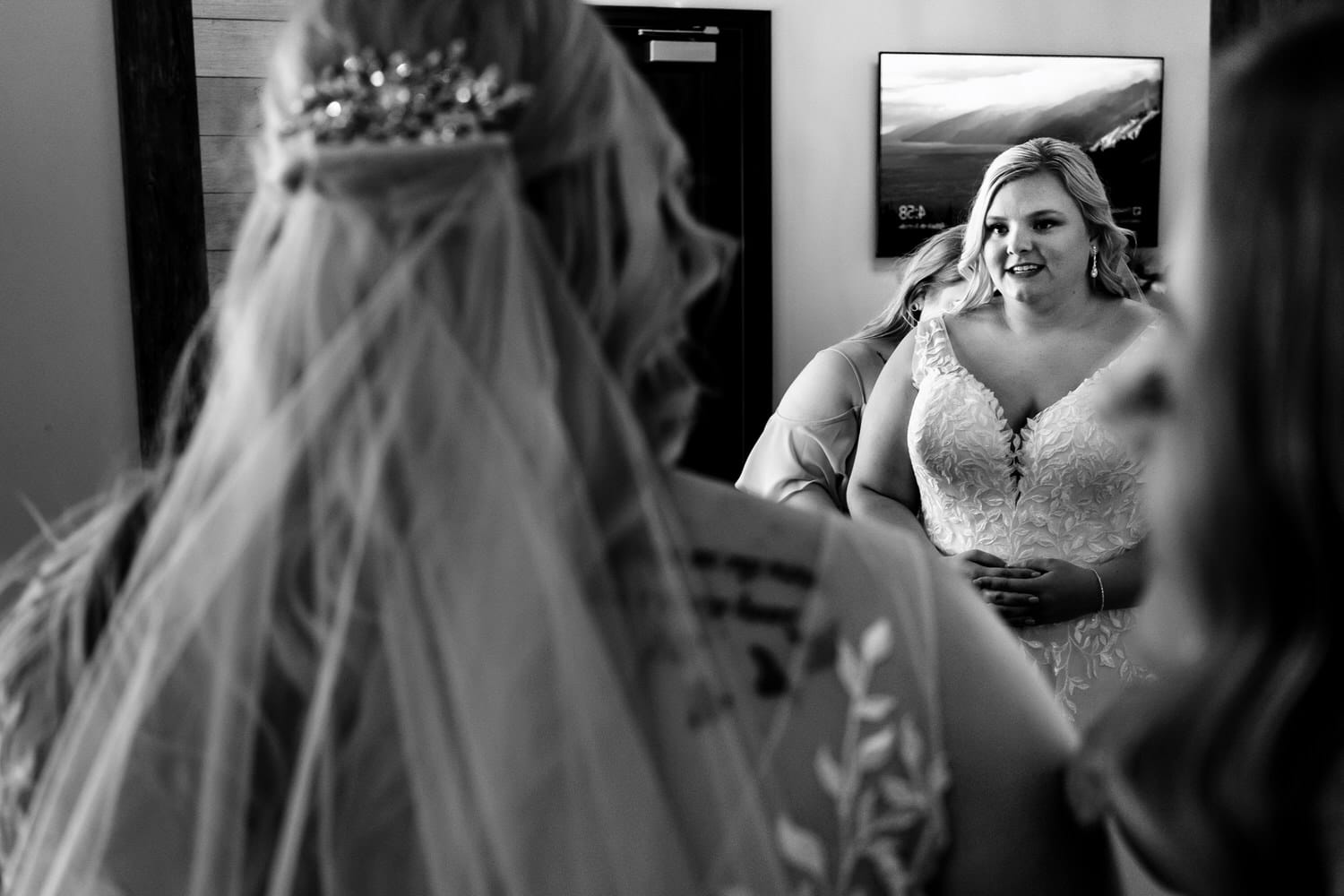 A candid black and white picture of a bride looking at her reflection in a mirror moments before walking down the aisle on her summer wedding day. 