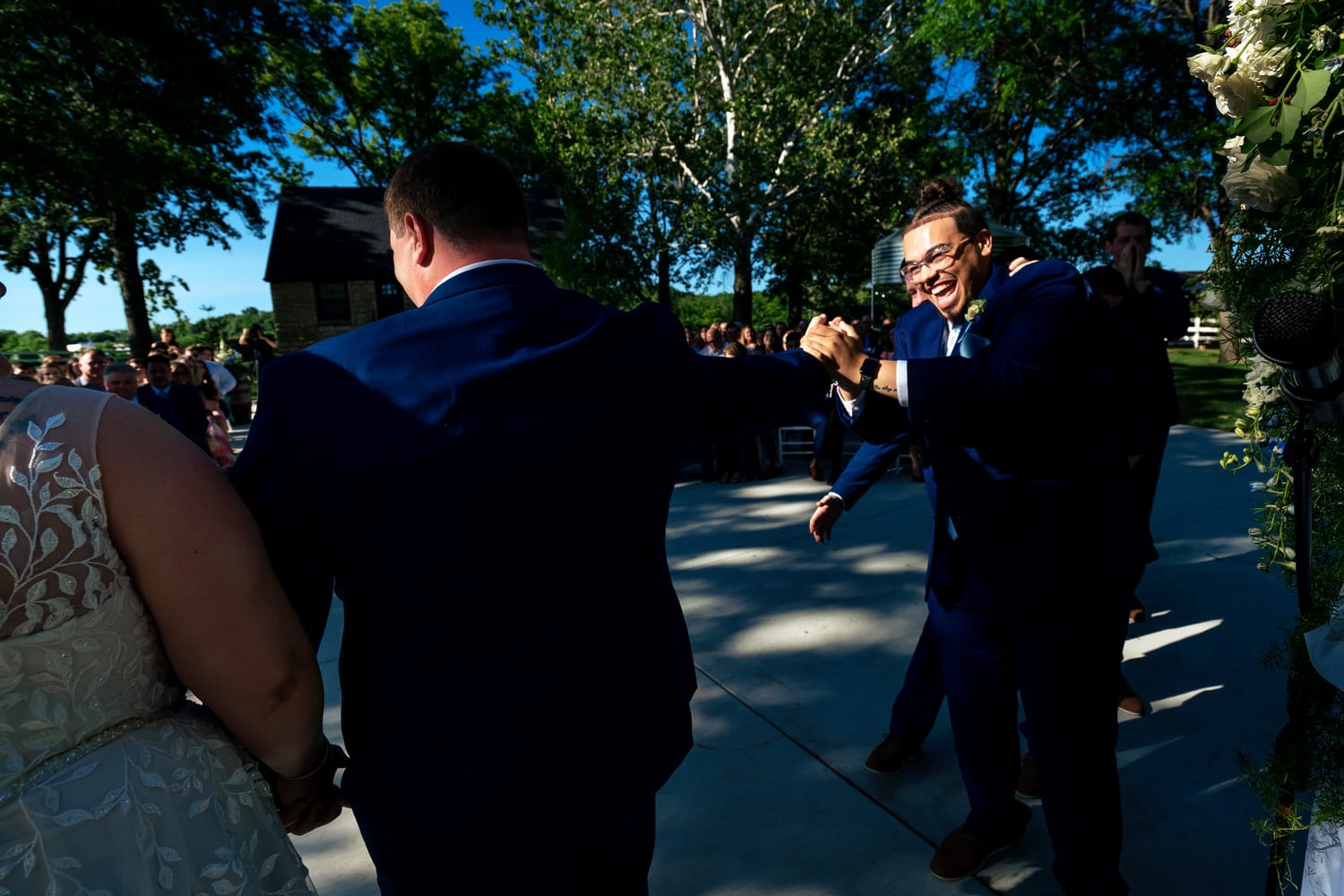 A candid picture of a best man fist bumping a groom at the end of a wedding ceremony at The Farmhouse KC Event Venue. 