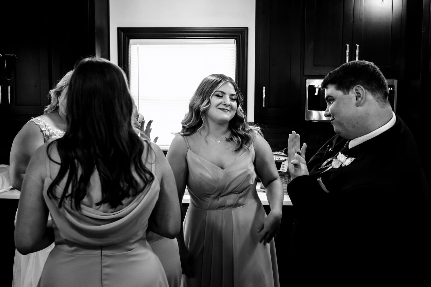 A candid black and white picture of a groom showing off his new wedding band to his little sister moments after a wedding ceremony. 