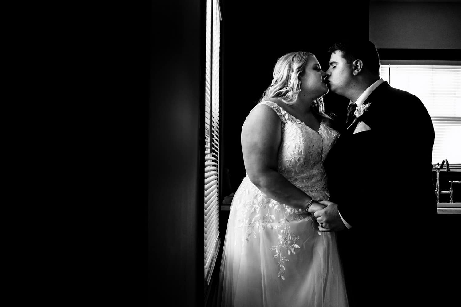 A candid black and white picture of a bride and groom sharing a kiss moments after their summer wedding ceremony at The Farmhouse KC Event Venue. 