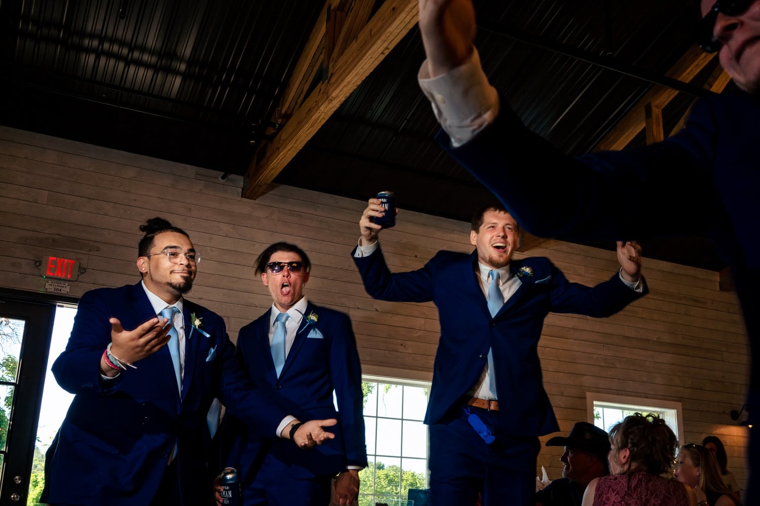 A candid, colorful picture of group of groomsmen entering a wedding reception, jumping in celebration. 
