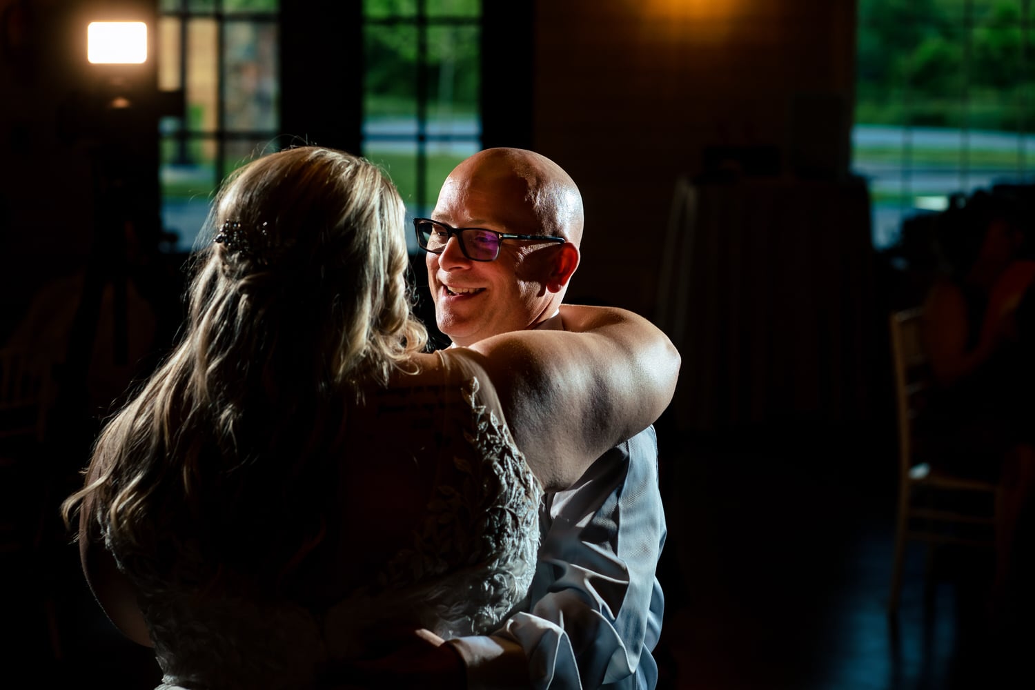 A candid picture of a father-daughter dance during a summer wedding reception at The Farmhouse KC Event Venue. 