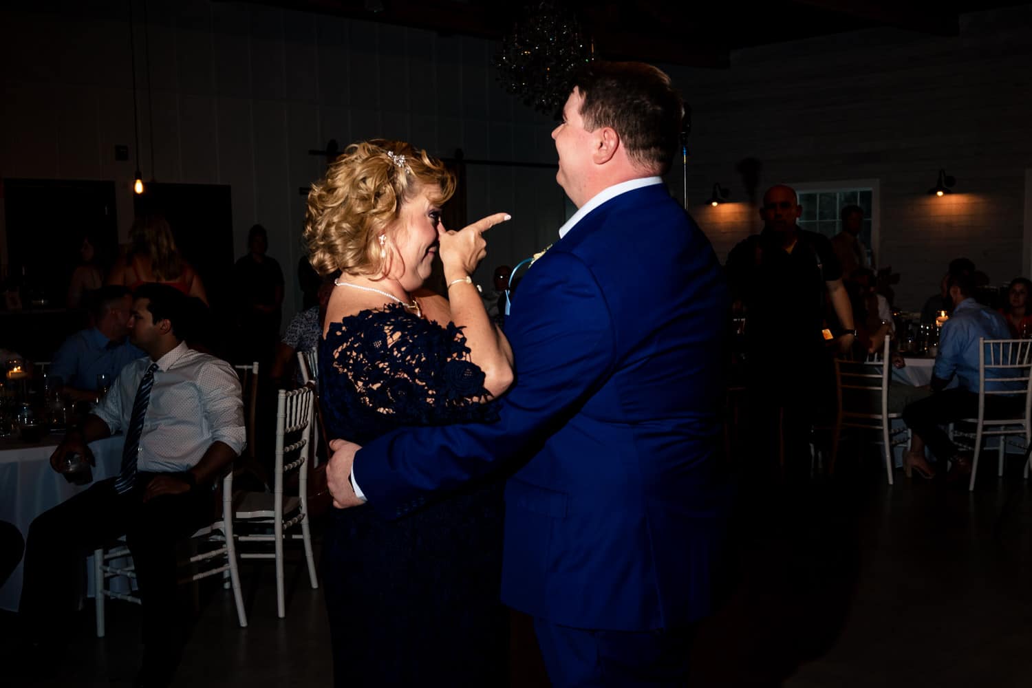 A candid picture of a mother-son dance during a summer wedding reception. 