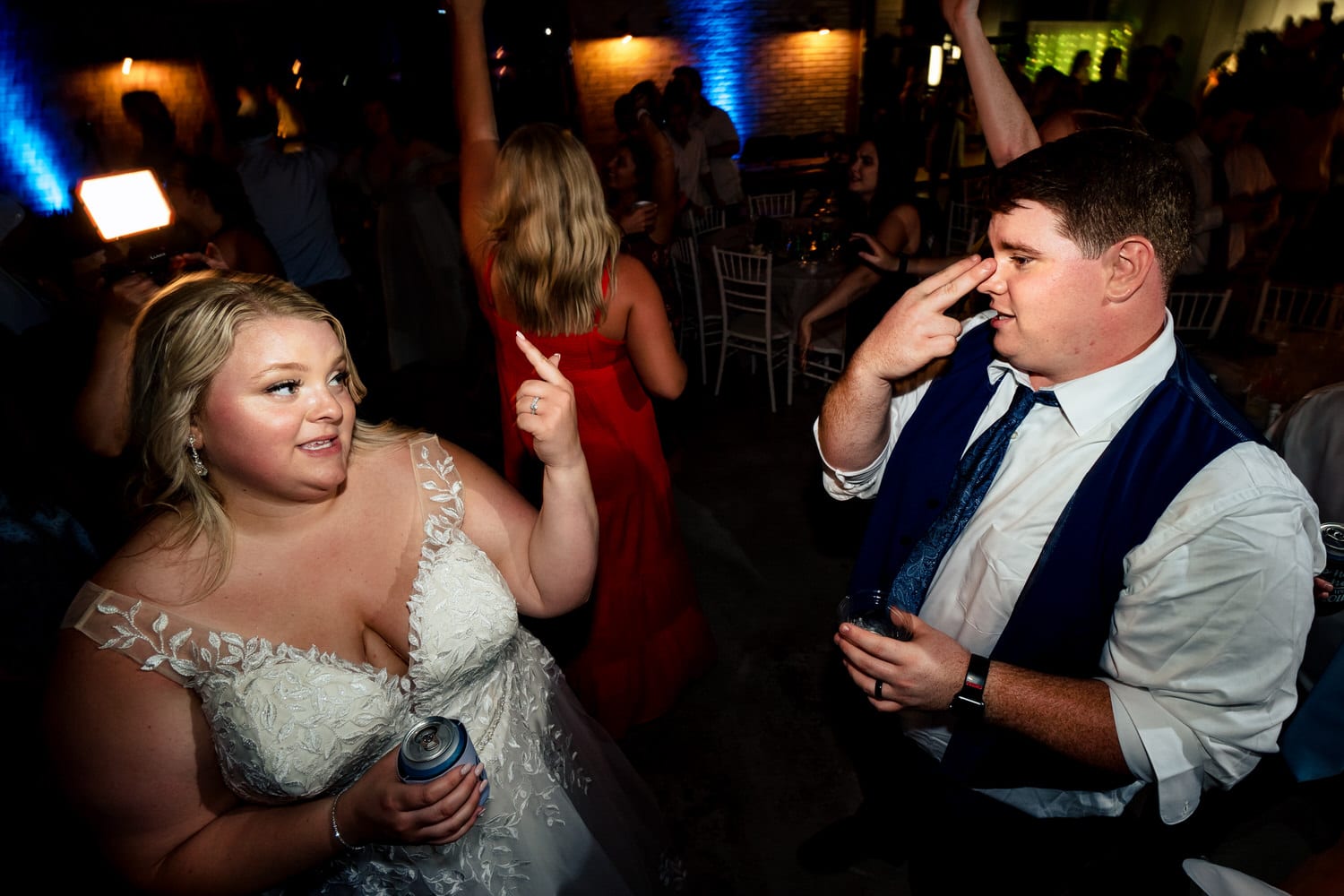 A fun, colorful picture of wedding guests dancing enthusiastically during a summer wedding reception at The Farmhouse KC Event Venue in Kansas City. 