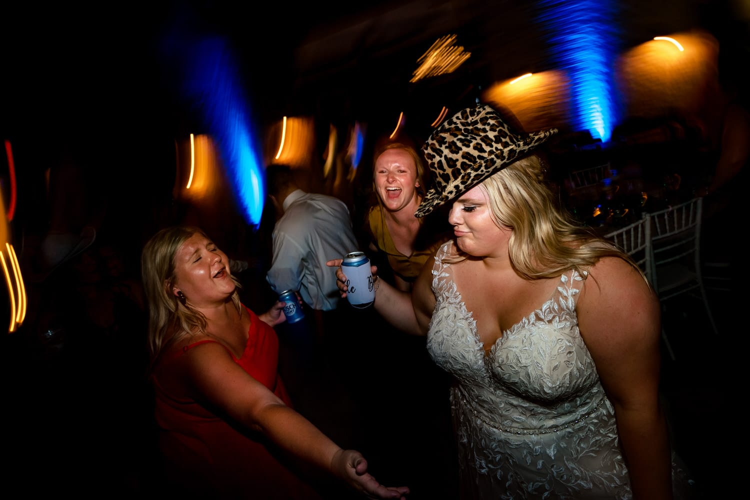 A fun, colorful picture of wedding guests dancing enthusiastically during a summer wedding reception at The Farmhouse KC Event Venue in Kansas City. 