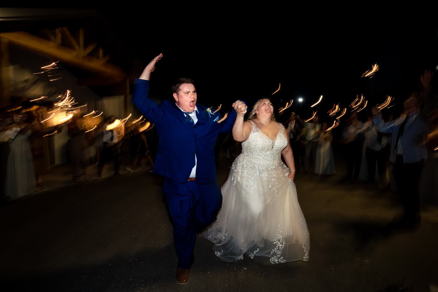 A candid picture of a bride and groom exiting their wedding reception with a sparkler exit. 