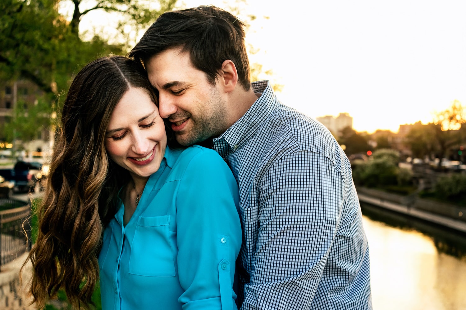 A colorful, candid picture of an engaged couple snuggling during their engagement session on the Kansas City Plaza. 