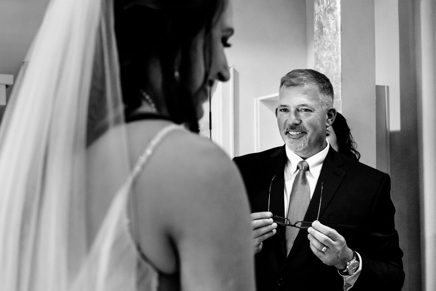 A candid black and white picture of a bride's father seeing her for the first time on her wedding day. 