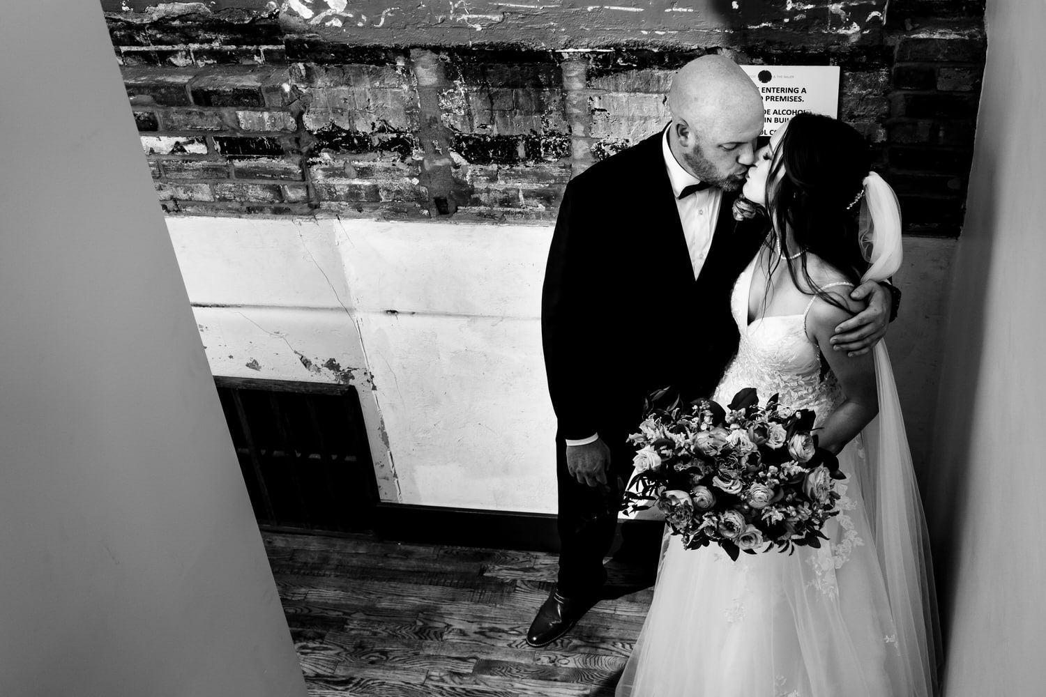 A dramatic black and white portrait of a bride and groom sharing an embrace at The Bride and The Bauer on their wedding day in Kansas City. 