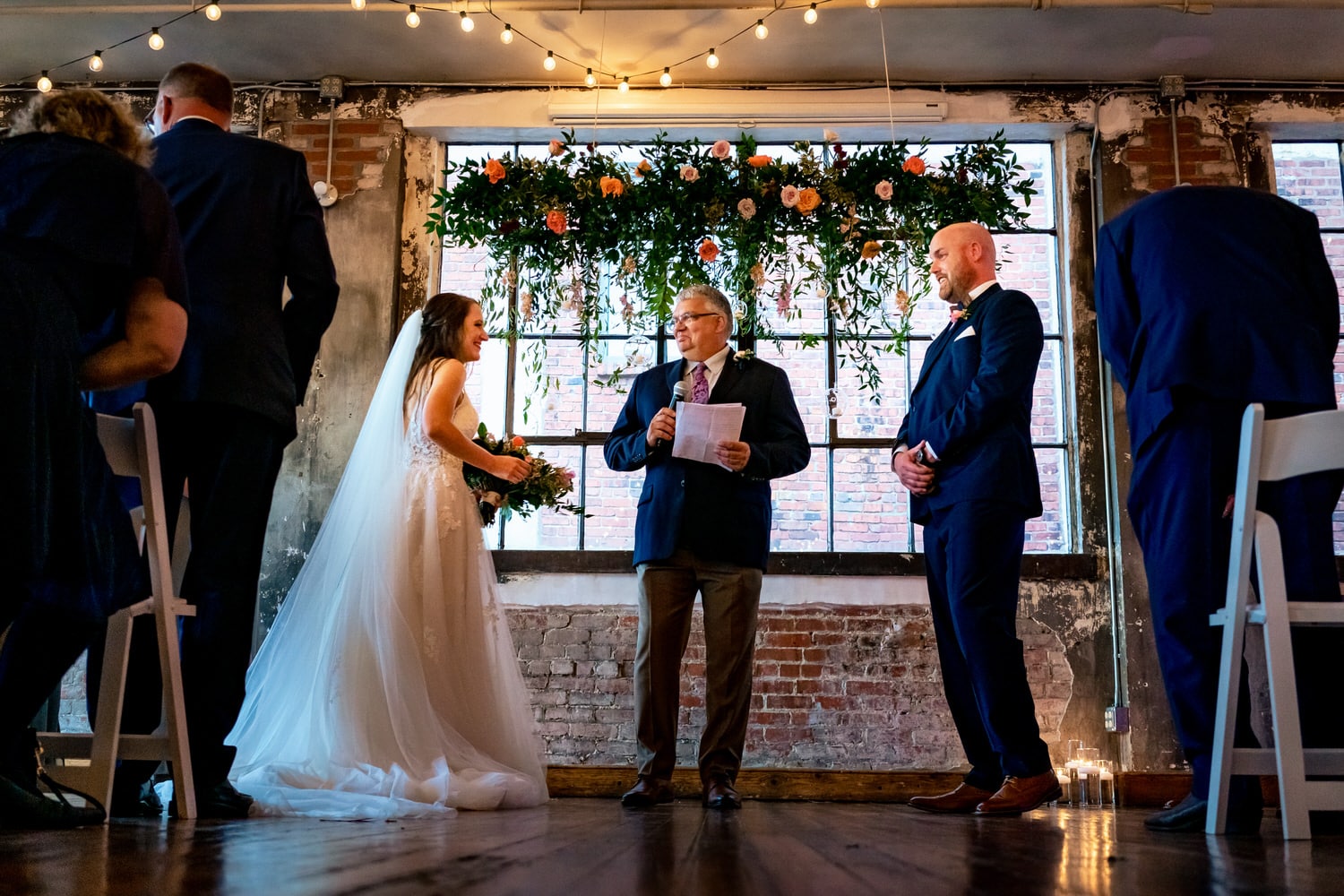 A colorful, candid picture of a bride and groom smiling at each other during their wedding ceremony at The Bride and the Bauer in Kansas City. 